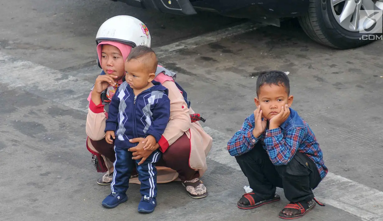 Pemudik bersama anak-anaknya saat menanti waktu masuk kapal penyebrangan di Dermaga 1 Pelabuhan Penyebrangan Merak, Banten, Sabtu (1/6/2019). Meski berbahaya, pemudik tetap nekat membawa anak berkendara sepeda motor menuju kampong halaman. (Liputan6.com/Helmi Fithriansyah)