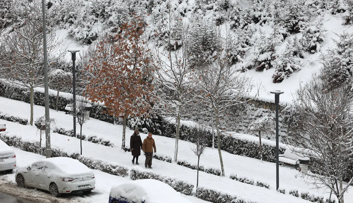 Warga melintasi jalan bersalju di Ankara, 23 Januari 2022.  Badai musim dingin dan hujan salju tetap berlaku di sebagian besar wilayah Turki, menyebabkan penutupan jalan antara ribuan desa dan kota di banyak daerah, beberapa hari setelah salju turun menyelimuti negara itu. (Adem ALTAN / AFP)