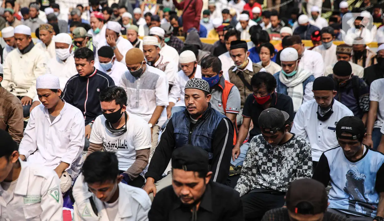 Massa aksi melaksanakan salat Ashar di sela unjuk rasa di Kawasan Patung Kuda, Jakarta, Selasa (13/10/2020). Massa aksi menolak Undang-Undang Cipta Kerja Omnibus Law tersebut salat beralaskan spanduk, kardus, hingga sajadah. (Liputan6.com/Faizal Fanani)