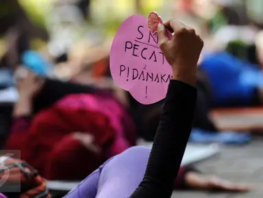Salah satu perempuan pegiat antikorupsi menunjukkan tulisan saat melakukan yoga dan aksi penyampaian pendapat di Taman Suropati, Jakarta, Minggu (6/12). Kegiatan ini juga bentuk peringatan Hari Anti korupsi. (Liputan6.com/Helmi Fithriansyah)