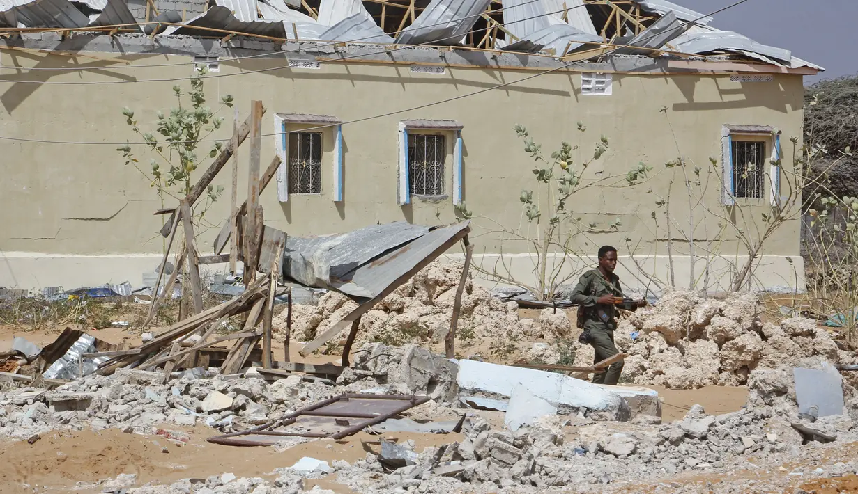 Anggota pasukan keamanan berjalan di samping bangunan yang sebagian hancur dalam serangan terhadap polisi dan pos pemeriksaan di pinggiran ibu kota Mogadishu, Somalia (16/2/2022). Serangan oleh kelompok ekstremis al-Shabab menewaskan lima orang dan melukai 16 orang. (AP Photo/Farah Abdi Warsameh)