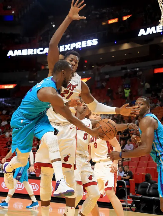 Kemba Walker #15 memberikan umpan kepada rekannya melewati adangan pebasket Miami Heat, Hassan Whiteside #21 pada laga NBA pre-season di American Airlines Arena, Miami, (9/10/2017). Miami Heat menang 109-106. (Mike Ehrmann/Getty Images/AFP)