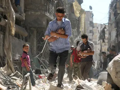 Para pria menggendong bayi saat berjalan melewati puing-puing bangunan yang hancur usai serangan udara di daerah yang dikuasai pemberontak di Salihin, Aleppo, Suriah, 11 September 2016. (Photo by Ameer al-HALBI/AFP)