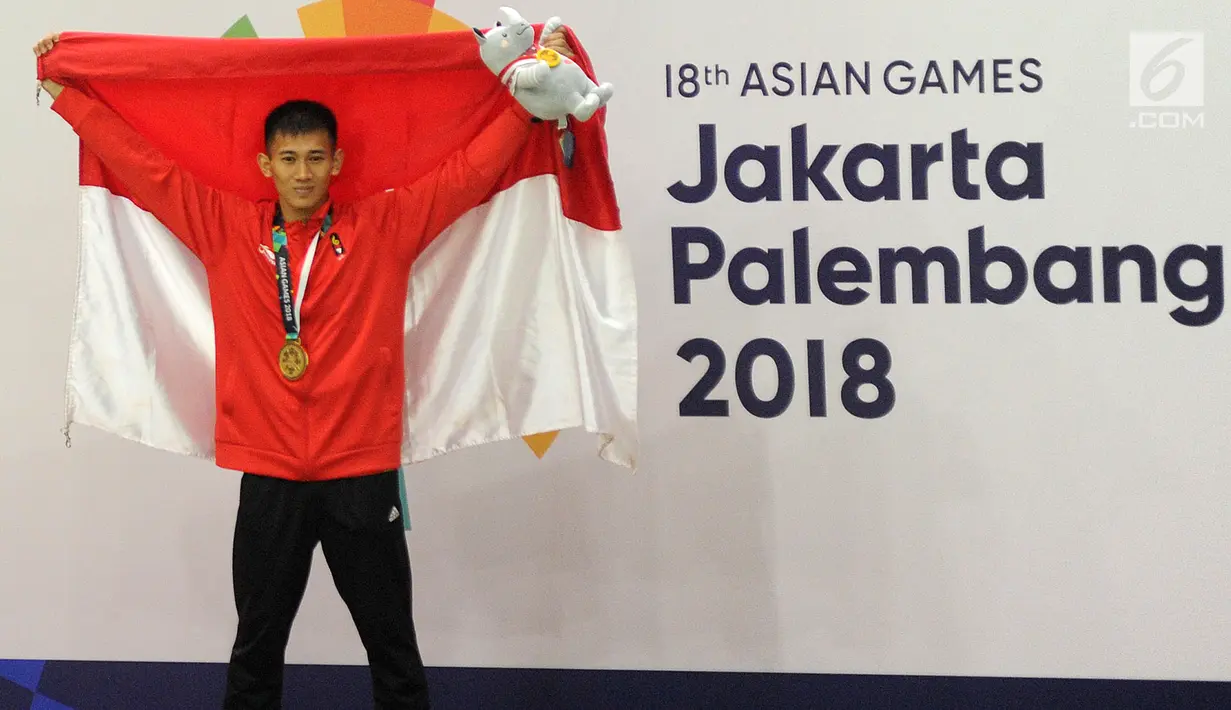 Pesilat Indonesia Iqbal Chandra Pratama mengangkat bendera Merah Putih usai menaklukkan Ngoc Toan Nguyen asal Vietnam di final Kelas D Putra Asian Games 2018 di Jakarta, Senin (27/8). Iqbal menang dan mendapatkan medali emas. (Merdeka.com/Arie Basuki)