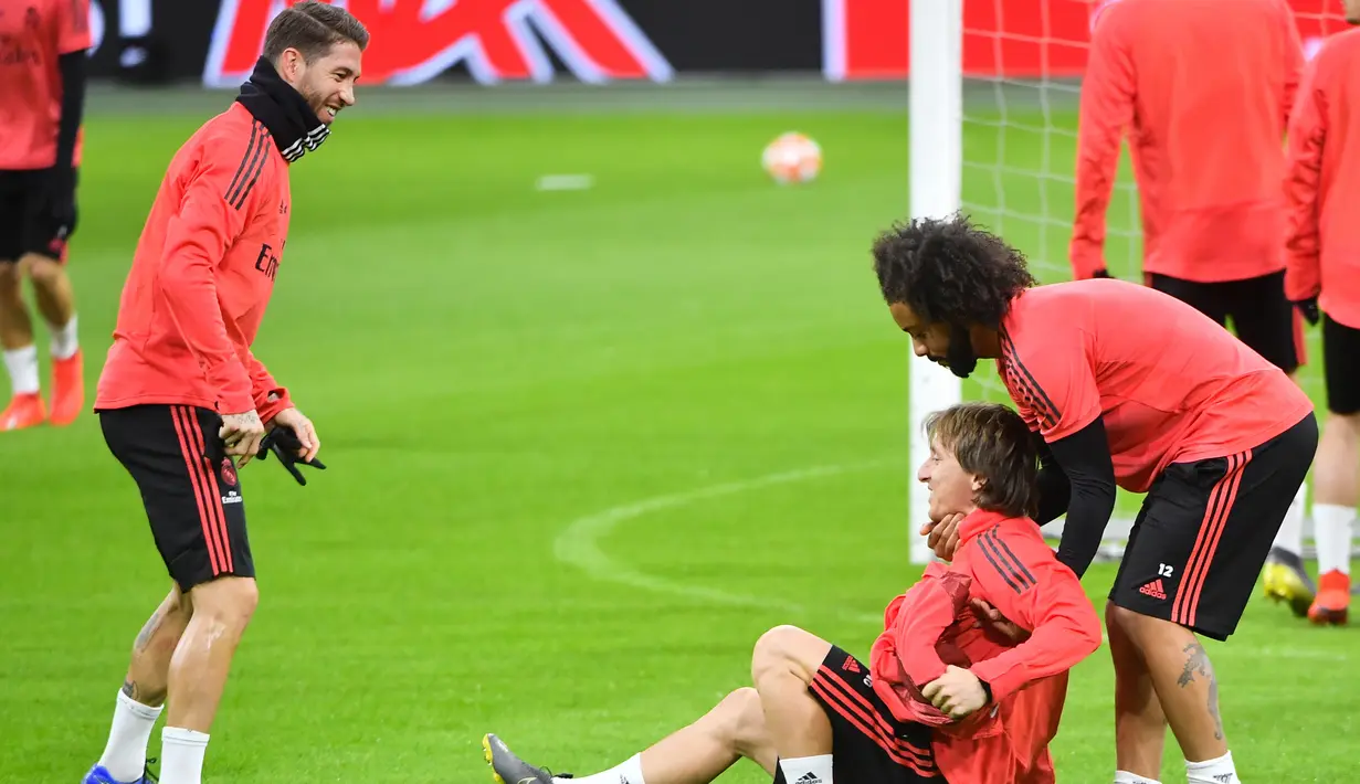 Bek Real Madrid, Marcelo, mengangkat Luka Modric, saat latihan jelang laga Liga Champions 2019 di Johan Cruijff Arena, Selasa (12/2). Real Madrid akan berhadapan dengan Ajax Amsterdam. (AFP/Emmanuel Dunand)
