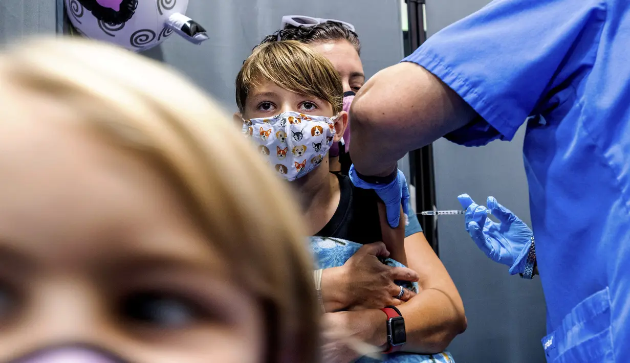 Finn Washburn (9) disuntik vaksin COVID-19 Pfizer-BioNTech saat adiknya, Piper Washburn (6) menunggu giliran saat vaksinasi anak 5 - 11 tahun di San Jose, California, Rabu (3/11/2021). Ini menjadi langkah perdana vaksinasi Covid-19 bagi anak kecil di Amerika Serikat. (AP Photo Noah Berger)