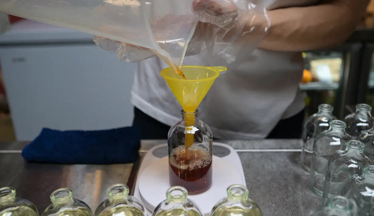 Seorang karyawan menuangkan minuman ExtraGineca, minuman yang terinspirasi oleh vaksin virus corona Covid-19, ke dalam botol kosong di sebuah bar koktail di George Town di pulau Penang, Malaysia (8/9/2021). (AFP/Mohd Rasfan)