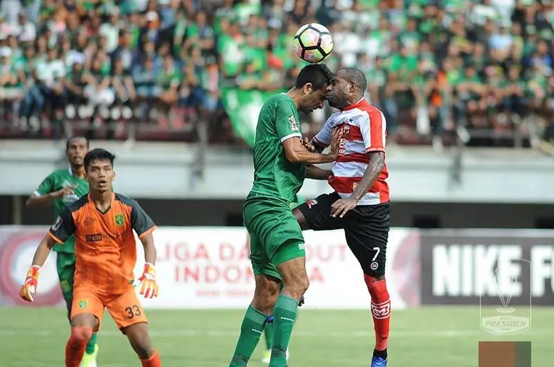 Bek Persebaya, Otavio Dutra, beradu kepala dengan pemain Madura United. (Liga Indonesia ID)