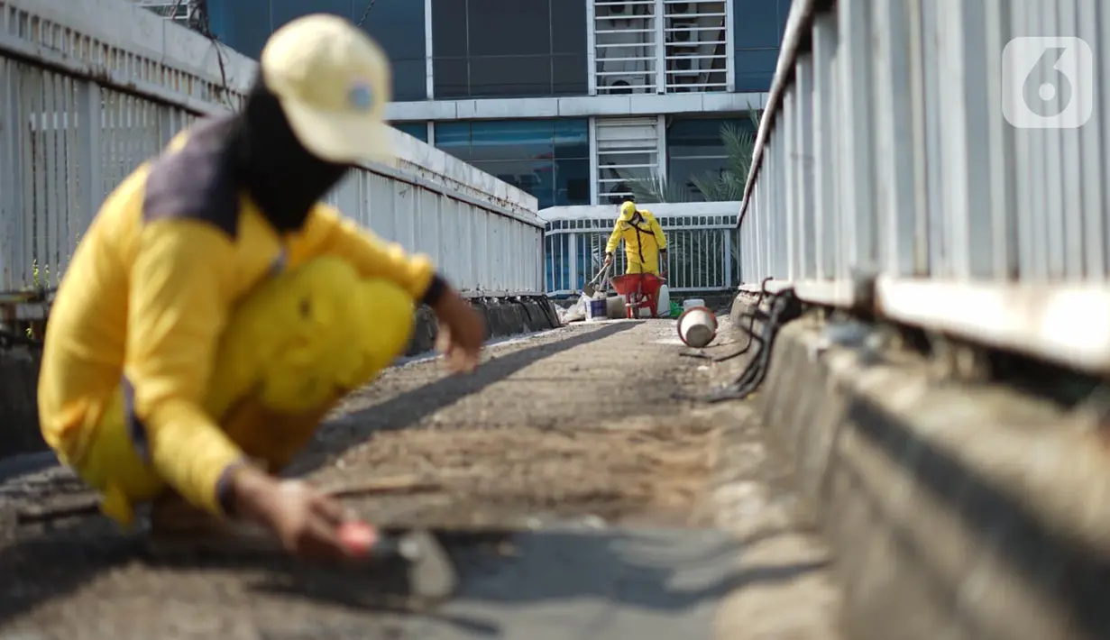 Petugas Bina Marga memerbaiki lantai Jembatan Penyeberangan Orang (JPO) yang berlubang di kawasan Tebet, Jakarta, Kamis (27/8/2020). Perbaikan dilakukan guna meningkatkan kenyamanan bagi pejalan kaki yang melintas. (Liputan6.com/Immanuel Antonius)
