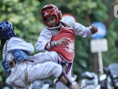 Murid Taekwondo Indonesia Manroe Club mengikuti latihan rutin di kawasan Kanal Banjir Timur (KBT), Jakarta Timur, Senin (16/8/2021). Taekwondo Manroe menggelar latihan di ruang terbuka akibat pemerintah meniadakan sementara olahraga di GOR selama pandemi COVID19. (merdeka.com/Iqbal S. Nugroho)