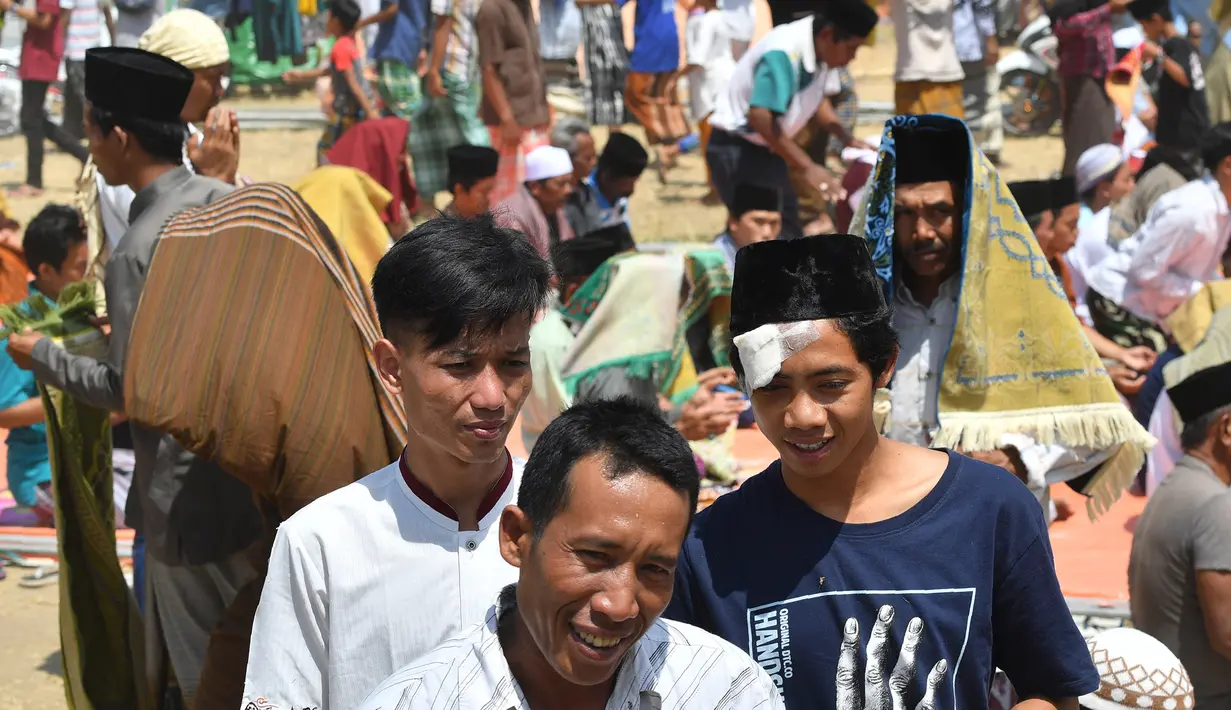 Umat muslim usai melaksanakan salat Jumat di sebuah ladang di dekat tempat penampungan sementara setelah gempa di Pemenang, Lombok (10/8). Jumlah Korban tewas akibat gempa dahsyat 6,9 SR di pulau Lombok melonjak di atas 300 orang. (AFP Photo/Adek Berry)