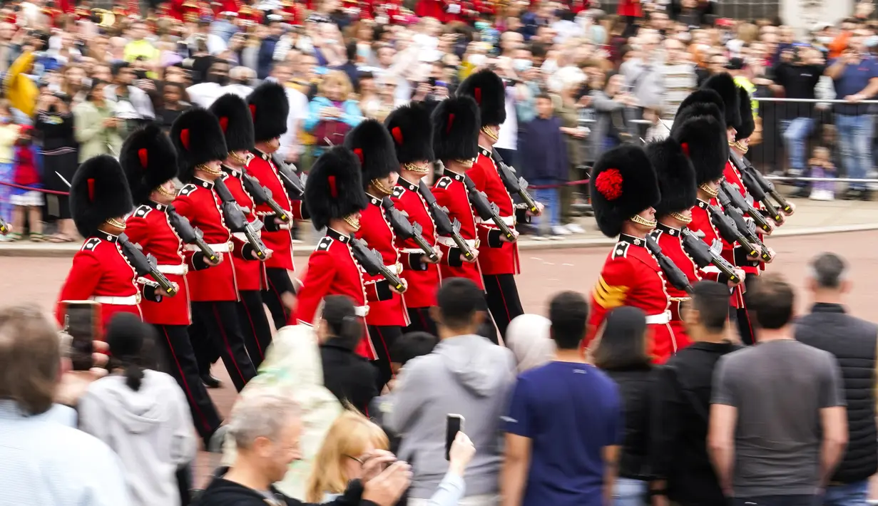 Orang-orang menyaksikan prosesi pergantian penjaga di Istana Buckingham, London, Senin (23/8/2021). Pergantian pasukan jaga yang dilengkapi dengan alat musik lengkap ala marching band tersebut berlangsung untuk pertama kalinya sejak dimulainya pandemi corona Covid-19. (AP Photo/Alberto Pezzali)
