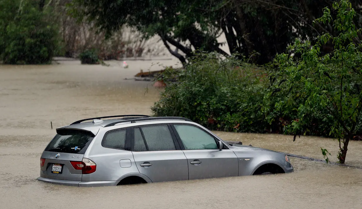 Sebuah mobil terendam di dekat Sungai Rusia yang meluap dan menyebabkan di Guerneville, California, AS, Selasa (10/1). Cuaca ektrem "Pineapple Express" yang membawa kelembapan dari Hawaii menciptakan hujan badai. (AP Photo / Eric Risberg)