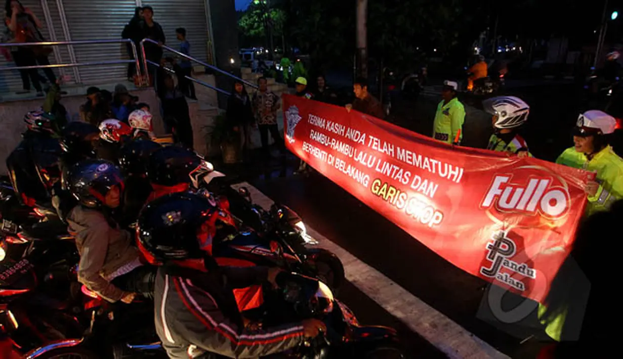 Petugas kepolisian Satlantas Jakarta Pusat membentangkan spanduk sosialisasi larangan berhenti pada garis stop di kawasan Cideng, Jakarta, Senin (23/2). (Liputan6.com/Johan Tallo)