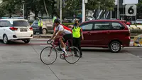 Polisi menghalau pesepeda yang berada di luar jalur di kawasan Sudirman-Thamrin, Jakarta Pusat, Rabu (2/6/2021). Sepeda road bike diperbolehkan untuk melintas di Jalan Sudirman-Thamrin pada hari kerja Senin-Jumat, namun dibatasi dari pukul 05.00-06.30 WIB. (Liputan6.com/Faizal Fanani)