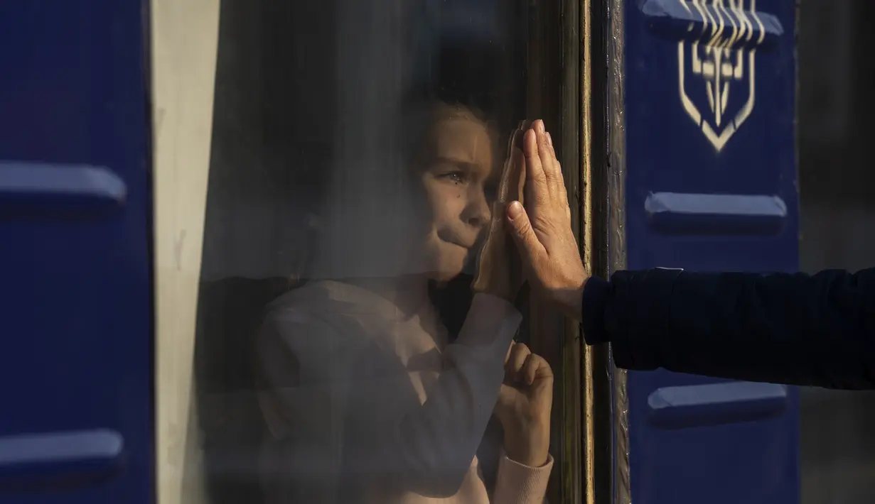 Ruslan Mishanin (kanan) berpamitan dengan putrinya yang berusia sembilan tahun saat kereta berangkat bersama keluarganya menuju Polandia, di stasiun kereta api di Odesa, pada Senin, 4 April 2022. (AP Photo/Petros Giannakouris)