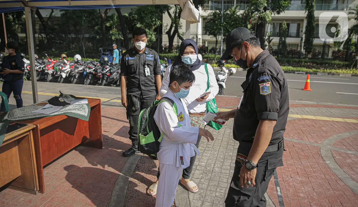 Petugas memeriksa suhu tubuh seorang anak di Lapangan Banteng, Jakarta, Sabtu (23/10/2021). Pemerintah Provinsi DKI Jakarta akan membuka 59 ruang terbuka hijau (RTH). (Liputan6.com/Faizal Fanani)