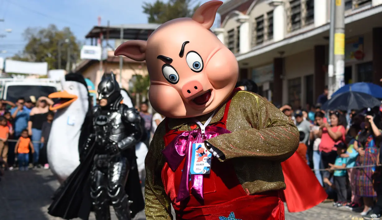 Anggota Saturno Club dengan kostum Three Little Piglets melakukan parade Dance of Costumes tahunan di sepanjang jalan kota Sumpango, Guatemala, Senin (30/12/2019). Parade kostum yang menampilkan karakter televisi dan film ini untuk memeriahkan malam pergantian tahun. (ORLANDO ESTRADA/AFP)
