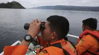 Tim SAR menggunakan teropong saat proses pencarian korban KM Sinar Bangun yang tenggelam di Danau Toba, Sumatra Utara, Rabu (20/6). Hingga hari ketiga, sebanyak 18 penumpang selamat, dua tewas dan 160 lainnya dalam proses pencarian. (AP/Binsar Bakkara)