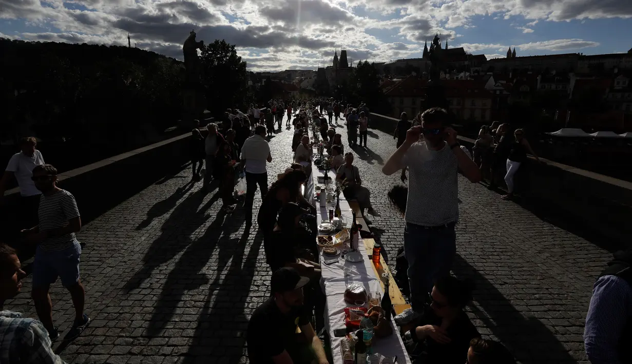 Warga menggelar makan malam di atas meja sepanjang 500 meter di jembatan bersejarah Charles Bridge di Praha, Republik Ceko, Selasa (30/6/2020). Kegiatan itu merupakan perpisahan simbolis yang digelar untuk menandai akhir dari masa krisis virus corona Covid-19 di negara tersebut (AP/Petr David Josek)
