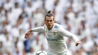 Pemain depan Real Madrid, Gareth Bale melompati bek Atletico Madrid Lucas Hernandez saat pertandingan La Liga Spanyol di stadion Santiago Bernabeu di Madrid (8/4). (AFP/Gabriel Bouys)
