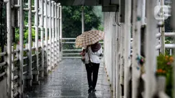 Pejalan kaki berjalan saat hujan lebat di JPO kawasan Jalan Sudirman, Jakarta, Selasa (29/6/2021). Hujan dan hawa dingin di musim kemarau karena ada gangguan atmosfer 'Indian Ocean dipole mode' yang masih negatif serta diperkirakan terjadi hingga akhir Juni. (Liputan6.com/Faizal Fanani)