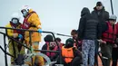 Para migran duduk di atas sekoci RNLI (Royal National Lifeboat Institution) setelah diselamatkan saat menyeberangi Selat Inggris di lepas pantai di Dungeness, Inggris tenggara (24/11/2021). (AFP/Ben Stansall)