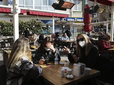 Para perempuan mengobrol sambil menunggu pesanan mereka di restoran yang dibuka kembalidi Ankara, Turki, Selasa (2/3/2021). Aktivitas bisnis seperti kafe dan restoran, diizinkan dibuka kembali dengan pembatasan kapasitas jumlah pengunjung serta jam operasional. (AP Photo/Burhan Ozbilici)