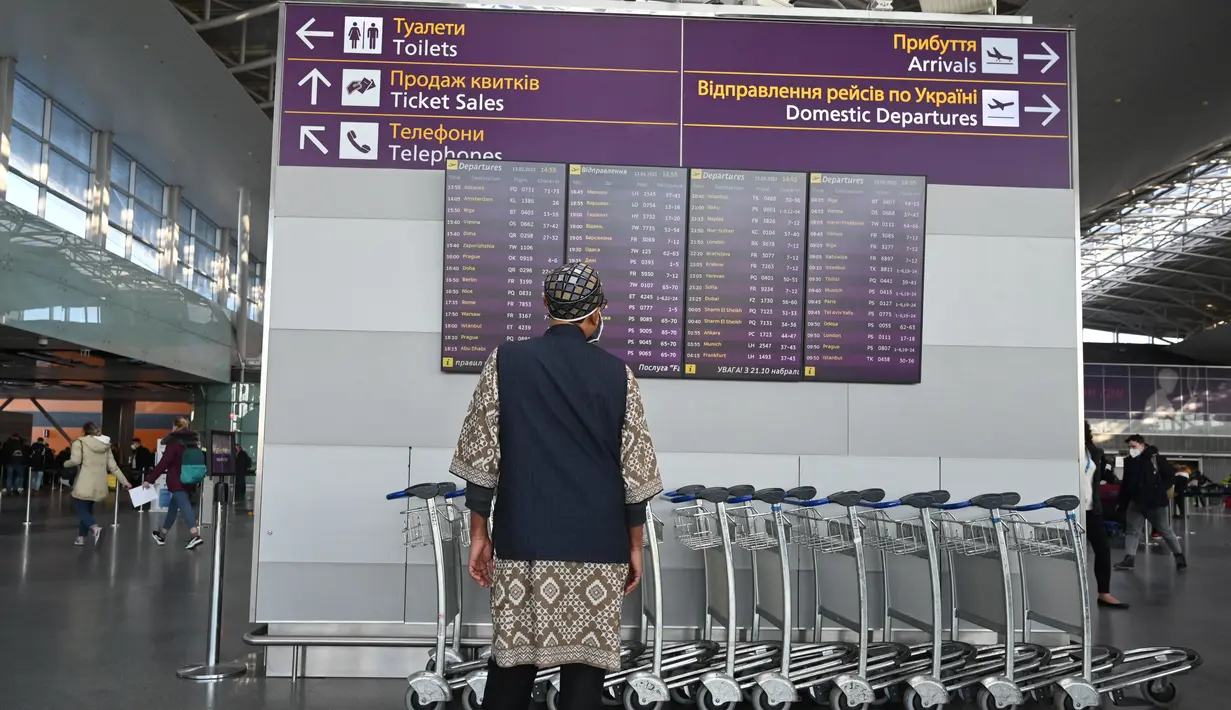 Seorang pria melihat papan keberangkatan sebelum penerbangannya di bandara Boryspil, luar Kiev, 13 Februari 2022. Ukraina berjanji menjaga wilayah udaranya terbuka untuk perjalanan internasional setelah negara Barat memperingatkan pasukan Rusia dapat menyerang kapan saja. (Sergei Supinsky/AFP)