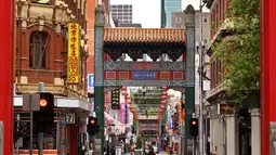 Orang-orang berjalan di jalan yang sepi di Chinatown Melbourne, Australia, Selasa (19/10/2021). Melbourne bersiap mencabut aturan penguncian pekan ini setelah kota tersebut berada dalam enam pekan lockdown selama 262 hari atau hampir sembilan bulan sejak Maret 2020. (William WEST/AFP)