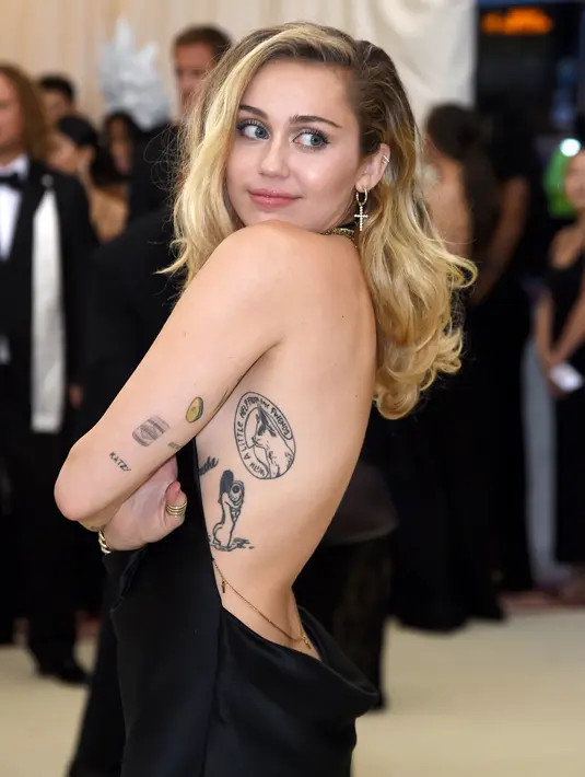 Penyanyi dan artis Hollywood, Miley Cyrus berpose setibanya pada ajang Met Gala 2018 di Metropolitan Museum of Art New York, Senin (7/5). Miley Cyrus tampil mengenakan gaun hitam yang memamerkan bagian punggung mulusnya. (Evan Agostini/Invision/AP)
