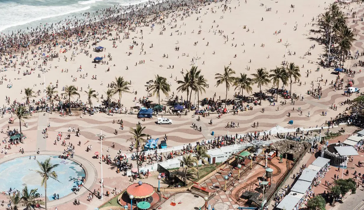 Ribuan wisatawan bersuka ria saat perayaan Tahun Baru di North Pier Beach, Durban, Afrika Selatan, 1 Januari 2022. Pemerintah Afrika Selatan mencabut pembatasan COVID-19 dengan menghapus jam malam dari tengah malam hingga pukul 04.00. (Rajesh JANTILAL/AFP)