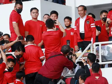 Presiden RI, Joko Widodo, memberikan senyuman saat melayani permintaan foto bersama suporter cilik di sela-sela rehat babak pertama pertandingan Timnas Indonesia melawan Thailand pada laga Piala AFF 2022 di Stadion Utama Gelora Bung Karno (SUGBK), Jakarta, Kamis (29/12/2022). (Bola.com/M Iqbal Ichsan)