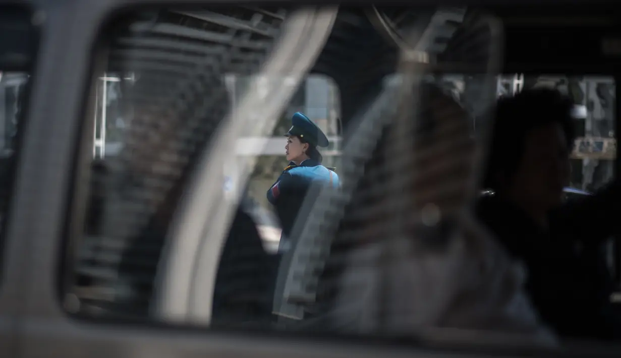 Seorang polisi wanita terlihat sedang memantau lalu lintas di Pyongyang, Korea Utara (5/6). Di Korea Utara menjadi polisi lalu lintas dipandang sebagai pekerjaan yang bergengsi. (AFP Photo/Ed Jones)