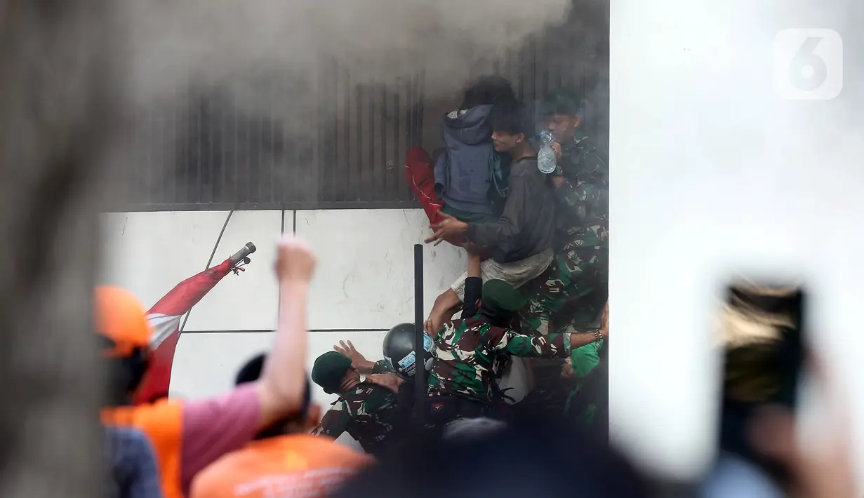 Melihat itu, massa dan personel TNI bahu membahu berupaya mengeluarkan penghuni tersebut dari dalam gedung. (Liputan6.com/Helmi Fithriansyah)