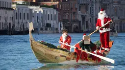 Seorang anak mengenakan kostum Santa Claus mendayung perahu di Canal Grande di Venesia, Italia, (17/12). Sekitar dua ratus pendayung memberikan kehidupan pada prosesi air tradisional Santa Claus. (Andrea Merola / ANSA via AP)