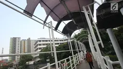 Pejalan kaki melintasi Jembatan Penyeberangan Orang (JPO) tanpa atap dan berkarat di Petamburan, Tanah Abang, Jakarta, Selasa (24/10). Selain itu kondisi tersebut juga membahayakan keselamatan pejalan kaki. (Liputan6.com/Immanuel Antonius)