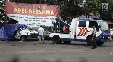 Petugas Ditlantas Polda Metro Jaya membawa mobil dinas polisi di Mapolsek Ciracas, Jakarta, Rabu (12/12). Ditlantas Polda Metro Jaya mengevakuasi sejumlah mobil yang rusak akibat penyerangan Polsek Ciracas. (Liputan6.com/Herman Zakharia)