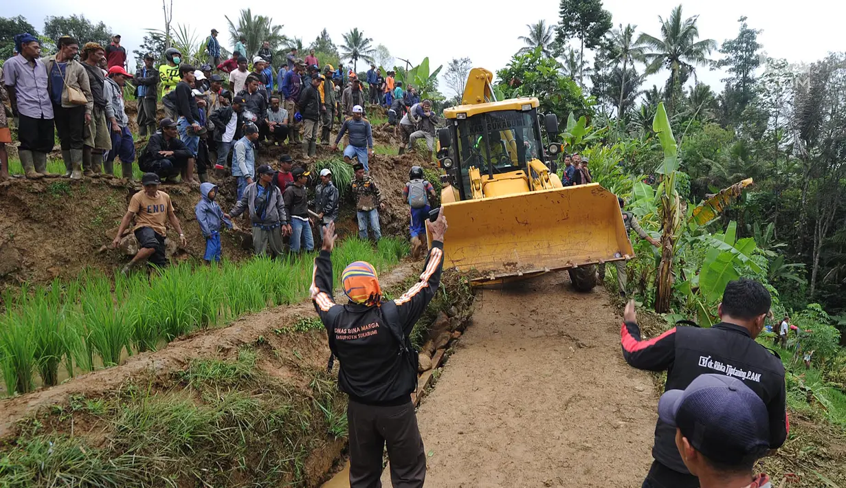 Warga memandu alat berat melalui jalan kecil menuju lokasi longsor di Dusun Cimapag, Sirnaresmi, Cisolok, Sukabumi, Jawa Barat, Selasa (1/1). Lokasi terpencil dan sempitnya jalan menyebabkan alat berat sulit masuk lokasi longsor. (Merdeka.com/Arie Basuki)