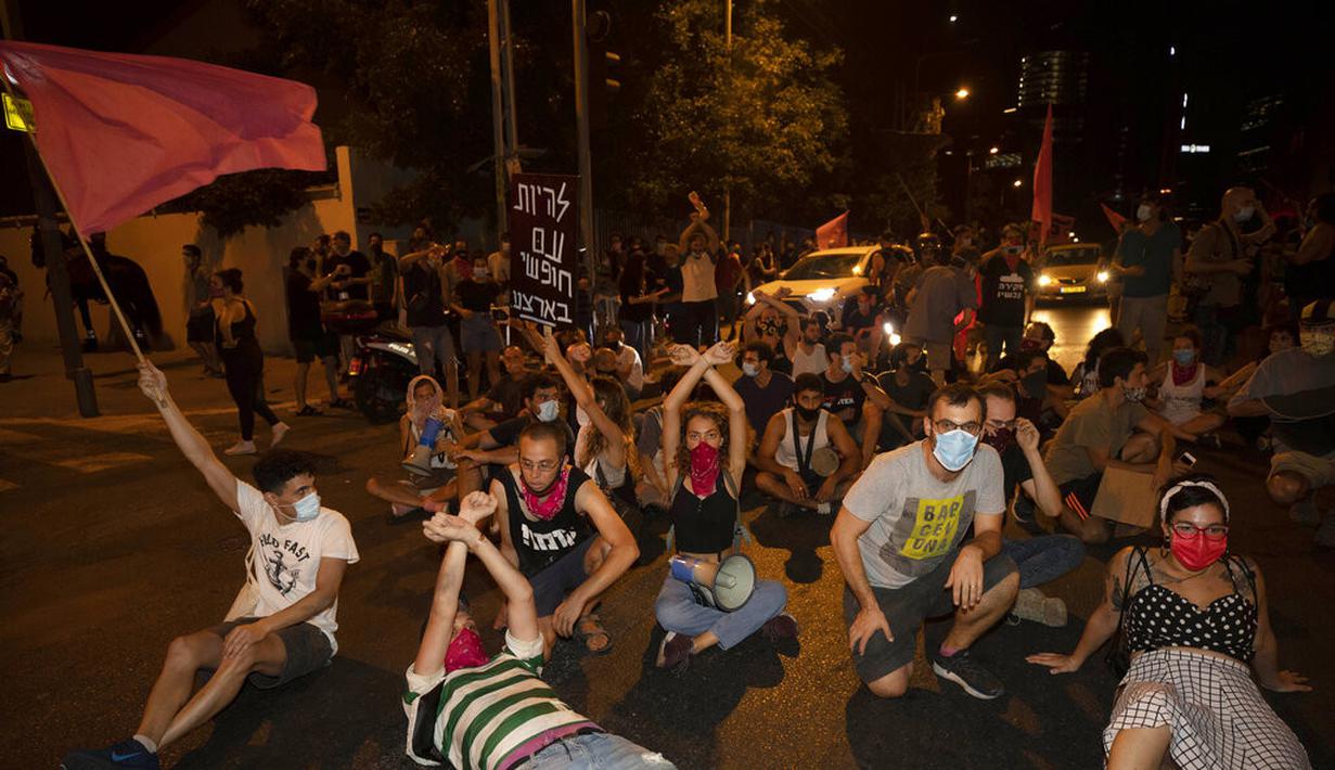 Pengunjuk rasa duduk di jalan selama demonstrasi menentang tindakan lockdown di Tel Aviv, Israel, Kamis (1/10/2020). Pengunjuk rasa meyakini lockdown ditujukan untuk mengekang protes terhadap Perdana Menteri Israel Benjamin Netanyahu. (AP Photo/Sebastian Scheiner)