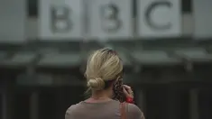 Seorang perempuan berjalan di luar Markas Besar BBC di London, Inggris, Selasa (11/7/2023). Detektif Inggris bertemu dengan perwakilan BBC pada hari Senin atas tuduhan bahwa seorang presenter terkemuka membayar seorang remaja untuk foto-foto eksplisit secara seksual. (AP Photo/Kin Cheung)