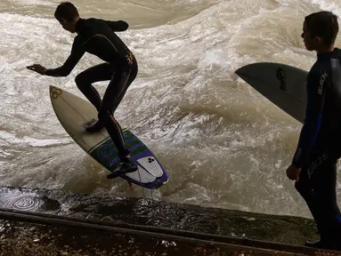 Peselancar meniti ombak saat bermain "surfing" di sungai buatan Eisbach yang terletak di English Garden Munich, Jerman pada 28 Mei 2019. Aliran air sungai Sungai Eisbach yang memiliki lebar 12 meter ini berasal dari Sungai Isar. (Photo by Peter Kneffel/dpa/AFP)
