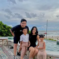 Keluarga kecil Rachel Vennya dan Okin dalam foto ini tampil dengan outfit kompak. Rachel mengenakan mini dress hitam tanpa lengan, sedangkan Okin kembali dengan kaus dan celana pendek yang semuanya berwarna hitam. Sedang kedua anaknya tampil gemas, abang dengan kemeja putih dan celana panjang cokelat, sedangkan adik tampil dengan set rajut atasan tanpa lengan dan celana panjangnya. Foto: Instagram.