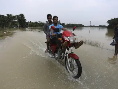 Seorang pengendara motor melewati jalan yang banjir di daerah Bagha di Sylhet, Bangladesh (23/5/2022). Banjir bandang pra-musim telah membanjiri bagian dari India dan Bangladesh, menewaskan sedikitnya 24 orang dalam beberapa pekan terakhir dan mengirim 90.000 orang ke tempat penampungan. (AP Photo)
