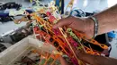 Pekerja menunjukkan bahan pendukung untuk membuat pelindung wajah di perusahaan Plaxtil, Chatellerault, Prancis, 25 Agustus 2020. Startup di Prancis, Plaxtil, mendaur ulang masker dan plastik untuk dijadikan pelindung wajah, pembuka pintu, dan pengencang masker. (GUILLAUME SOUVANT/AFP)