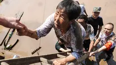 Pejabat desa mengevakuasi penduduk dari daerah banjir setelah hujan lebat di Dazhou di provinsi Sichuan barat daya China (12/7/2021). Banjir akibat hujan lebat melanda sejumlah wilayah di China. (AFP/STR)