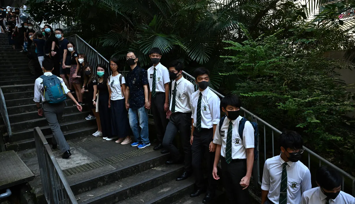 Para siswa, alumni dan guru saling memegang tangan di area Mid-Levels, Hong Kong, Senin (9/9/2019). Aksi dilakukan para siswa yang masih berseragam sekolah sambil memakai masker sebagai bentuk dukungan terhadap demonstran anti pemerintah setelah bentrokan pada akhir pekan. (Anthony WALLACE/AFP)