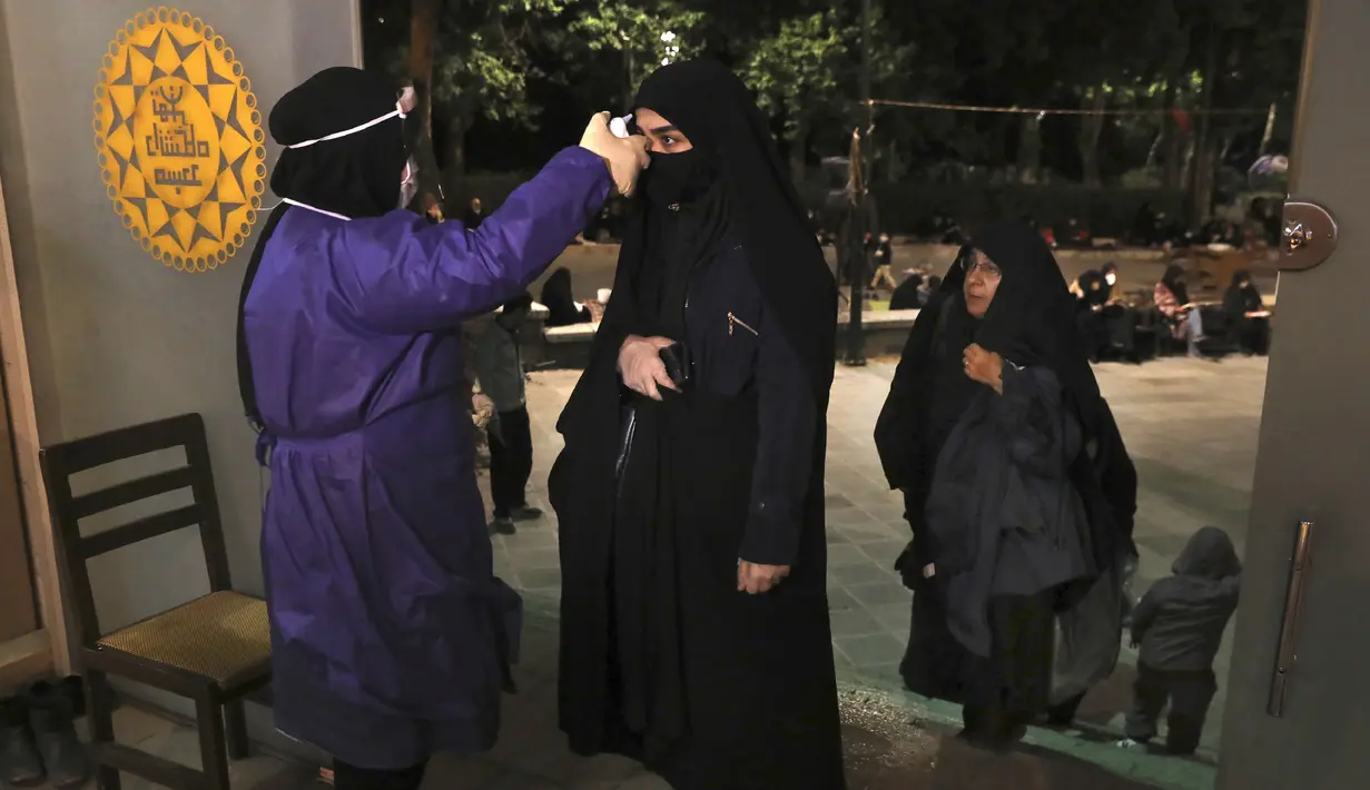 Jemaah diperiksa suhu tubuhnya saat akan memburu malam lailatul qadar di Masjid Universitas Teheran, Laylat al-Qadr, Iran, Selasa (12/5/2020). Iran mengizinkan masjid dibuka kembali, namun dengan memperhatikan prosedur kesehatan dan sosial untuk mencegah penyebaran COVID-19. (AP Photo/Vahid Salemi)