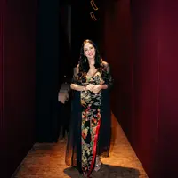 Meriam Bellina sebagai mamah Diah, tampak elegan dengan dress hitam dengan motif penuh nuansa kehijauan. Dress tersebut ia padukan bersama mesh long outer. [Dok/Gampang Cuan Film]