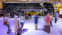 Pengunjung mengambil foto bus single doubel decker (SDD) yang mengangkut mobil sport dalam gelaran GIIAS 2019 di ICE BSD, Tangerang, Jumat (19/9/2019). Bus SDD, Adiputro memiliki sistem entertainment berupa smart tv, subwoofers, 10 speakers, preamplifier dan DVD player. (Liputan6.com/Ferbian Pradolo